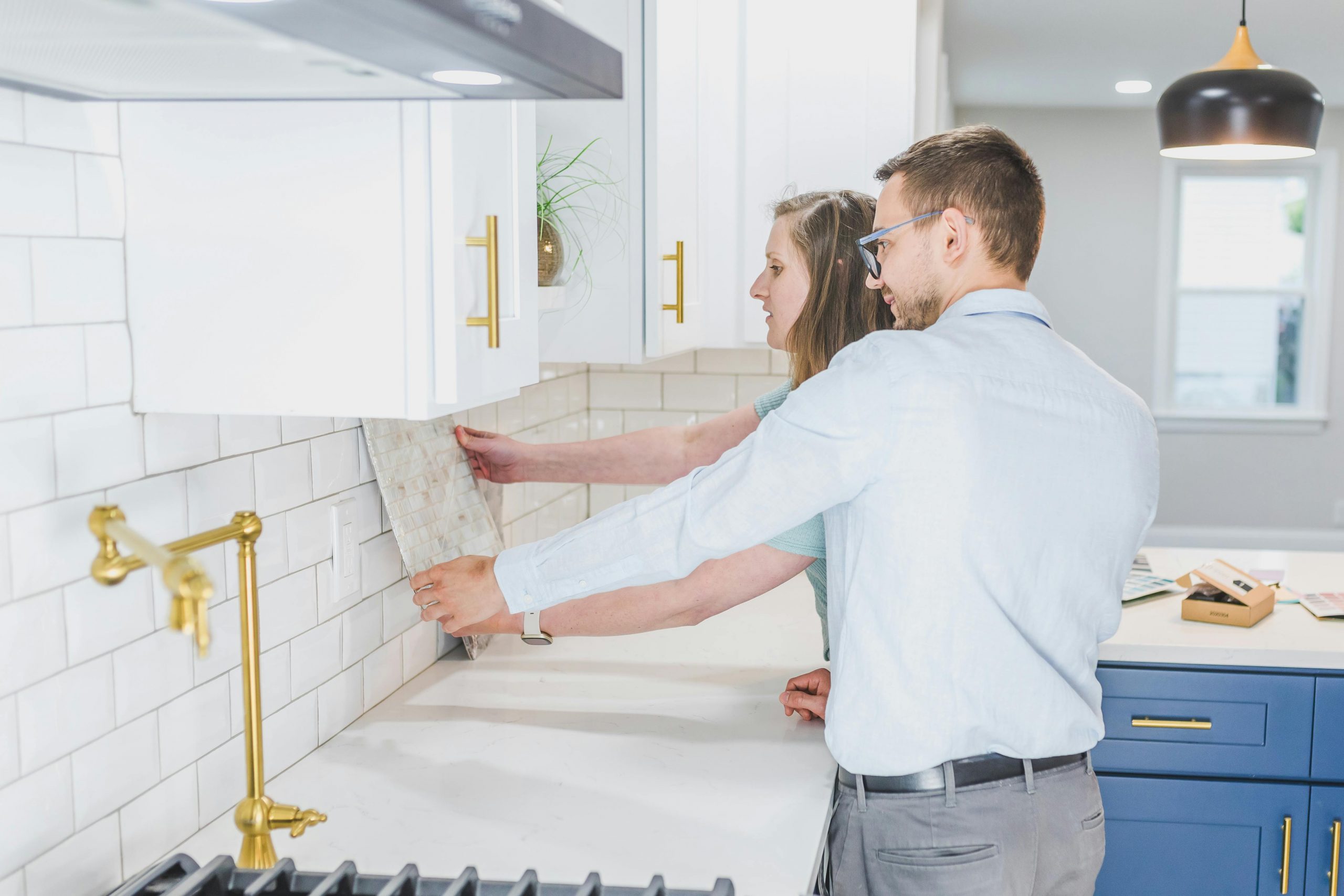 A couple examines backsplash tiles for their modern kitchen renovation.
